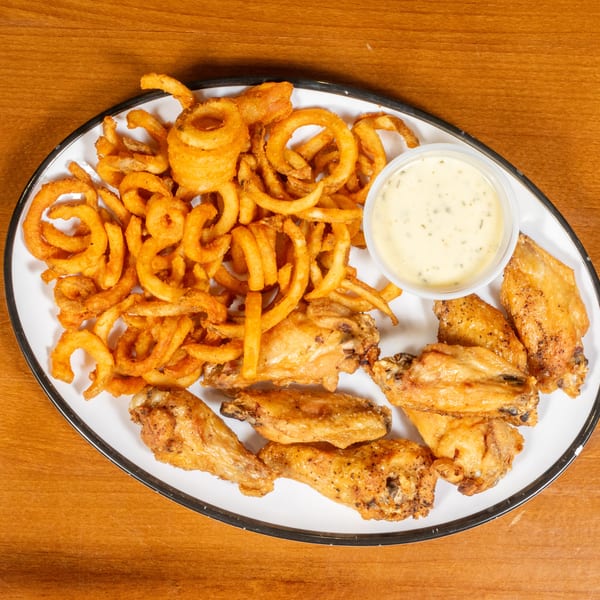 A white platter with crispy golden curly fries, chicken wings, and a side of ranch dressing.