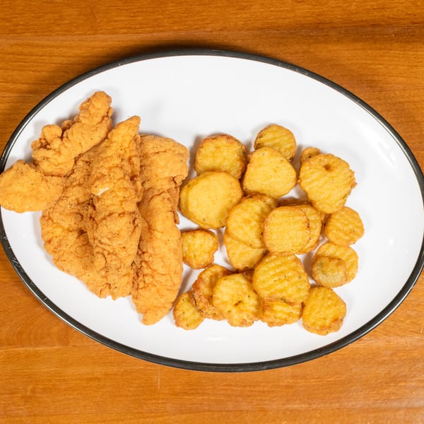 A white oval plate with black rim holds golden-brown chicken tenders and crispy waffle-cut fries.